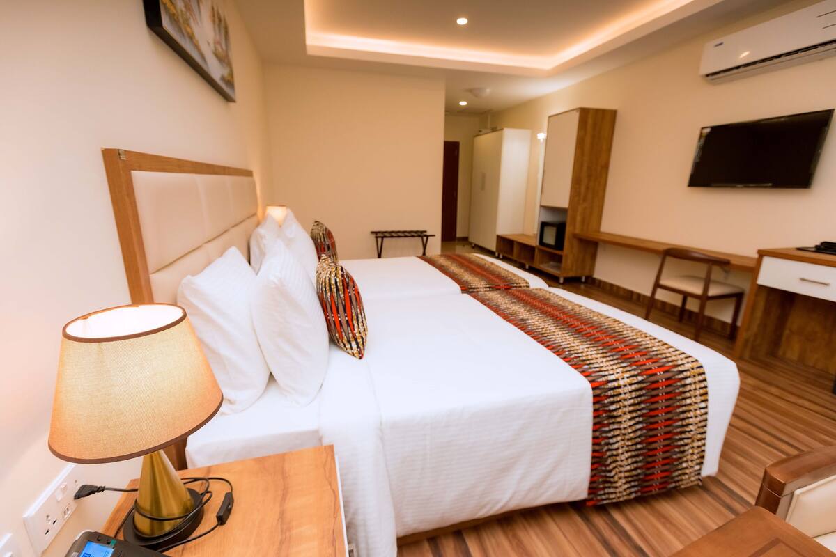 Ein Hotelzimmer mit Bett, Schreibtisch, Stuhl, Lampe und Fernseher.
