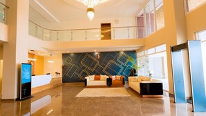 A spacious lobby with a high ceiling, a reception desk, a seating area with sofas, and a large chandelier. - The Hut Restaurant & Boutique hotel (Kigali)
