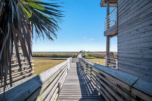 Une promenade en bois mène à une plage, et un bâtiment en bois se trouve sur la droite.