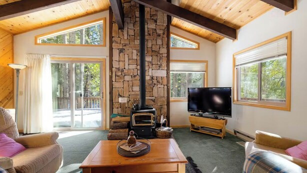 Una sala de estar acogedora con chimenea de piedra, televisión y asientos cómodos.