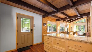 Una cocina con armarios de madera, encimera de granito y ventana con vistas a un jardín.