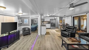 A modern living room with a flat-screen TV, leather sofas, and a dining area with a table and chairs.