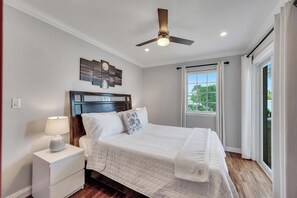 A bedroom with a bed, nightstand, ceiling fan, and a window with curtains. - Steps from the Beach / Heated Pool / Seaside Key (Fort Lauderdale)