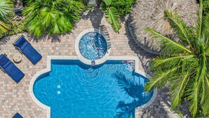 A swimming pool with a circular hot tub, surrounded by palm trees and lounge chairs. - Steps from the Beach / Heated Pool / Seaside Key (Fort Lauderdale)