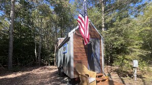 Une petite cabane avec une véranda, une chaise berçante et un drapeau américain.
