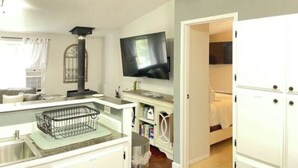 Une petite chambre comprenant un coin cuisine, une télévision et un lit.