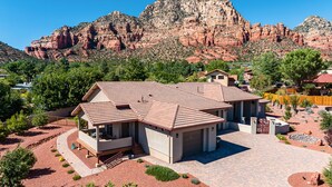 A modern house with a spacious patio, surrounded by a landscaped garden and a mountain backdrop. - Experience luxury at Sedona Thunder Mountain Estate and Casita in West Sedona. (Sedona)