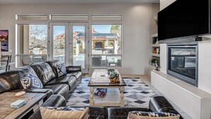 A modern living room with a leather sofa, a coffee table, and a flat-screen TV mounted on the wall. - Experience luxury at Sedona Thunder Mountain Estate and Casita in West Sedona. (Sedona)