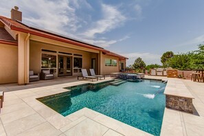 Une maison moderne dotée d’une piscine, d’un espace salon extérieur et d’un coin barbecue.