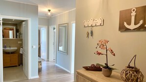 Ein modernes Interieur mit Holzboden, einer Küchenzeile mit Spüle und Schränken sowie einem Gang, der in einen anderen Raum führt.
