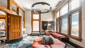 A spacious room with a large window, a circular ceiling light, a sofa, and a remote control on the floor. - Sundial B409-B | Ski-in/Ski-out | Private Balcony | Washer/Dryer | Mountain Views | Pools & Hot Tubs (Park City)