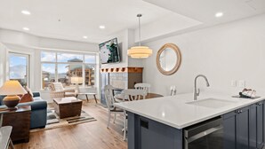 Une cuisine moderne dotée d’un grand îlot central, d’un coin repas avec des chaises et d’une vue sur une montagne.
