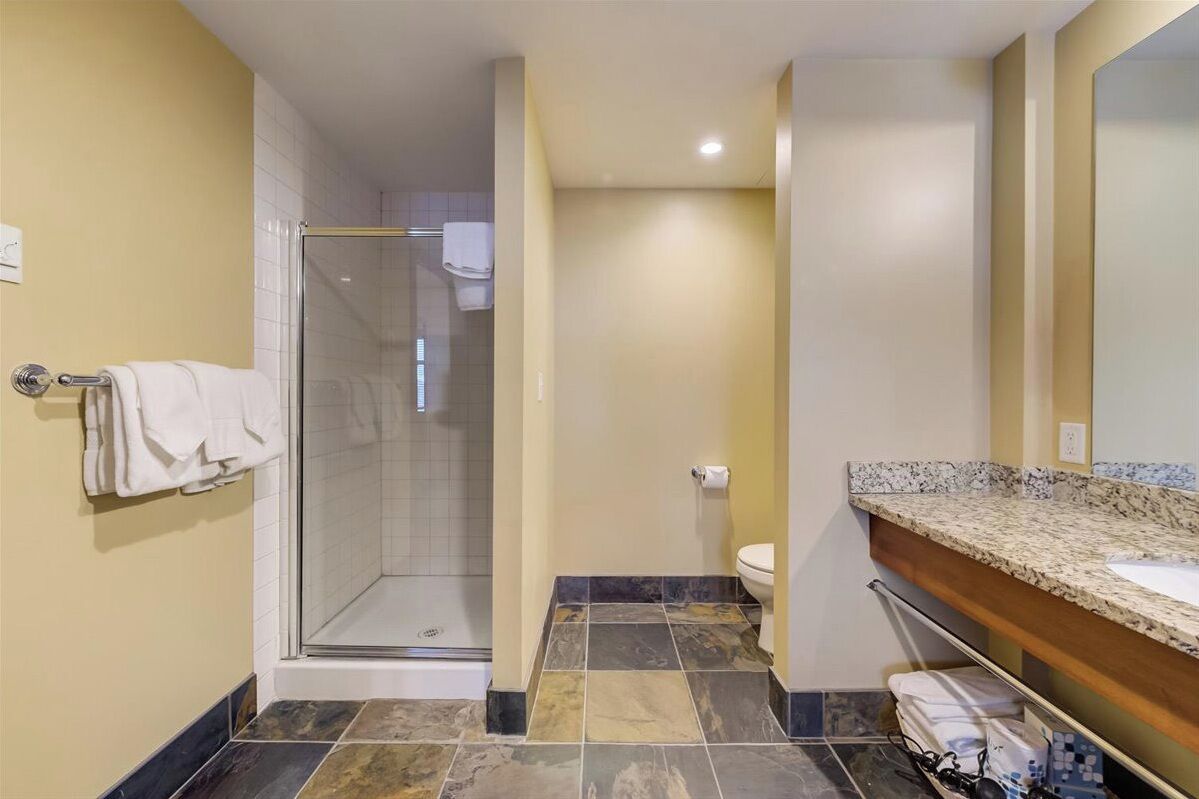 Une salle de bain moderne avec une douche à parois de verre, des toilettes et un lavabo sur un plan de travail en granit.