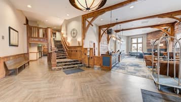 Un hall d’entrée spacieux, agrémenté d’un grand escalier, de poutres en bois et d’un comptoir d’accueil.