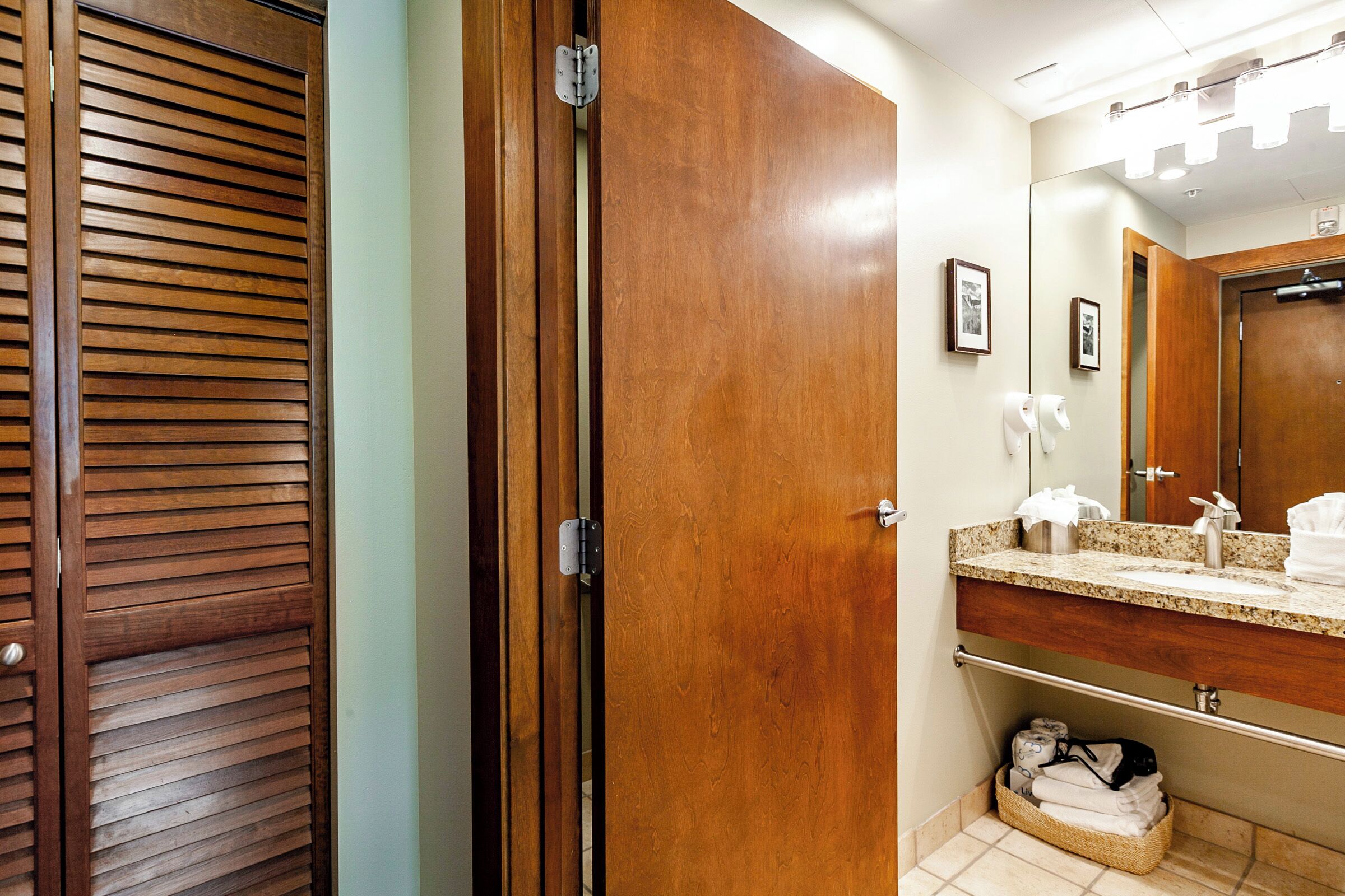 Ein Badezimmer mit Holztür, Waschbecken mit Spiegel und Handtuchhalter.