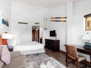 A hotel room with a bed, a desk, a chair, a TV, and a painting on the wall. - Sundial C407-A | Ski-in/Ski-out | Village Views | Pools & Hot Tubs | Fitness Room (Park City)