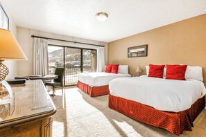 A hotel room with two beds, a desk, a chair, a large window with curtains, and a view of the outside. - Shadow Ridge 114-1 | 150 Yards to Slopes | Mountain Views | Food Galley | Pool & Hot Tub | Sauna (Park City)