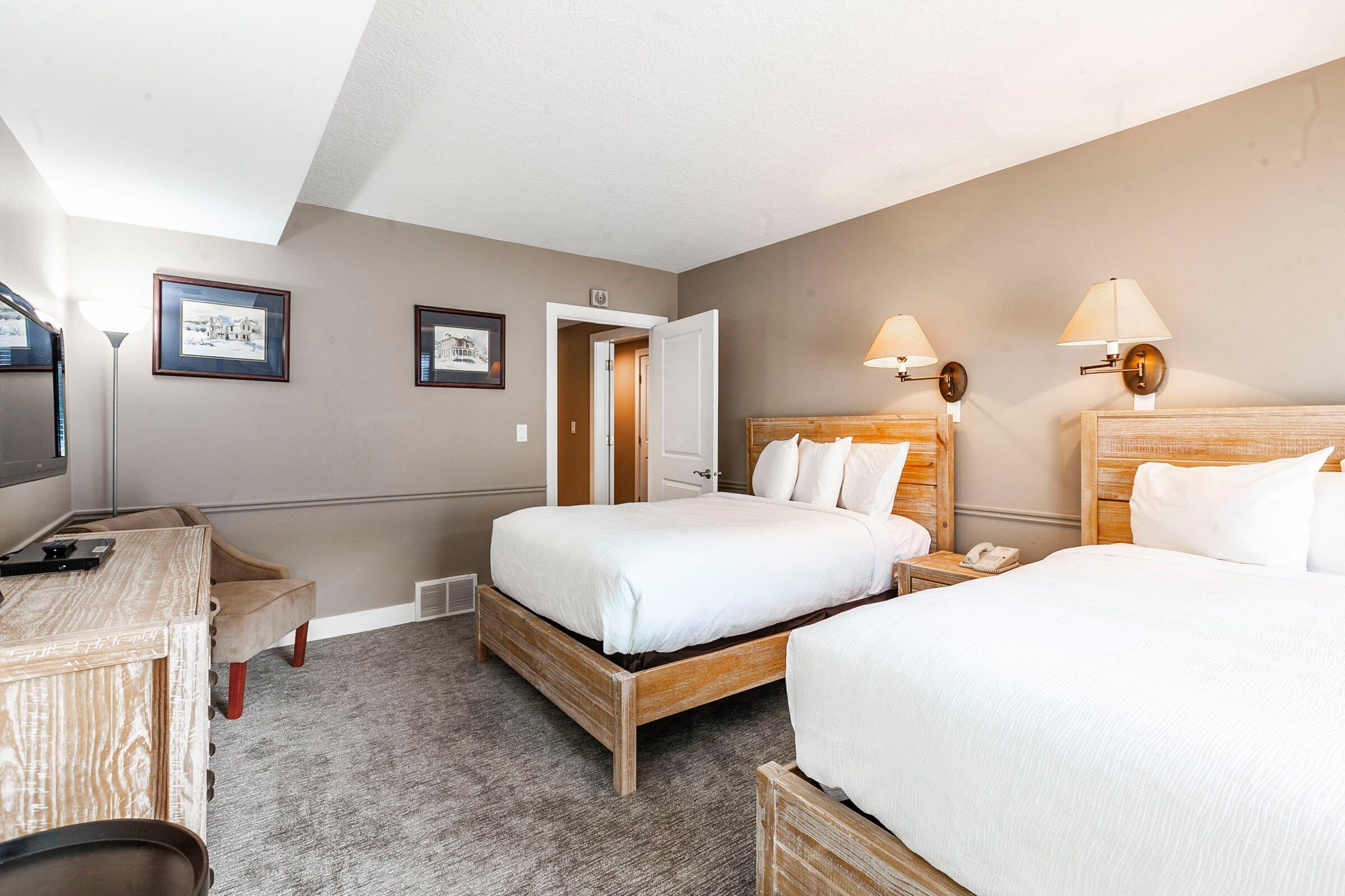 A hotel room with a bed, bedside tables, a desk, and a chair.