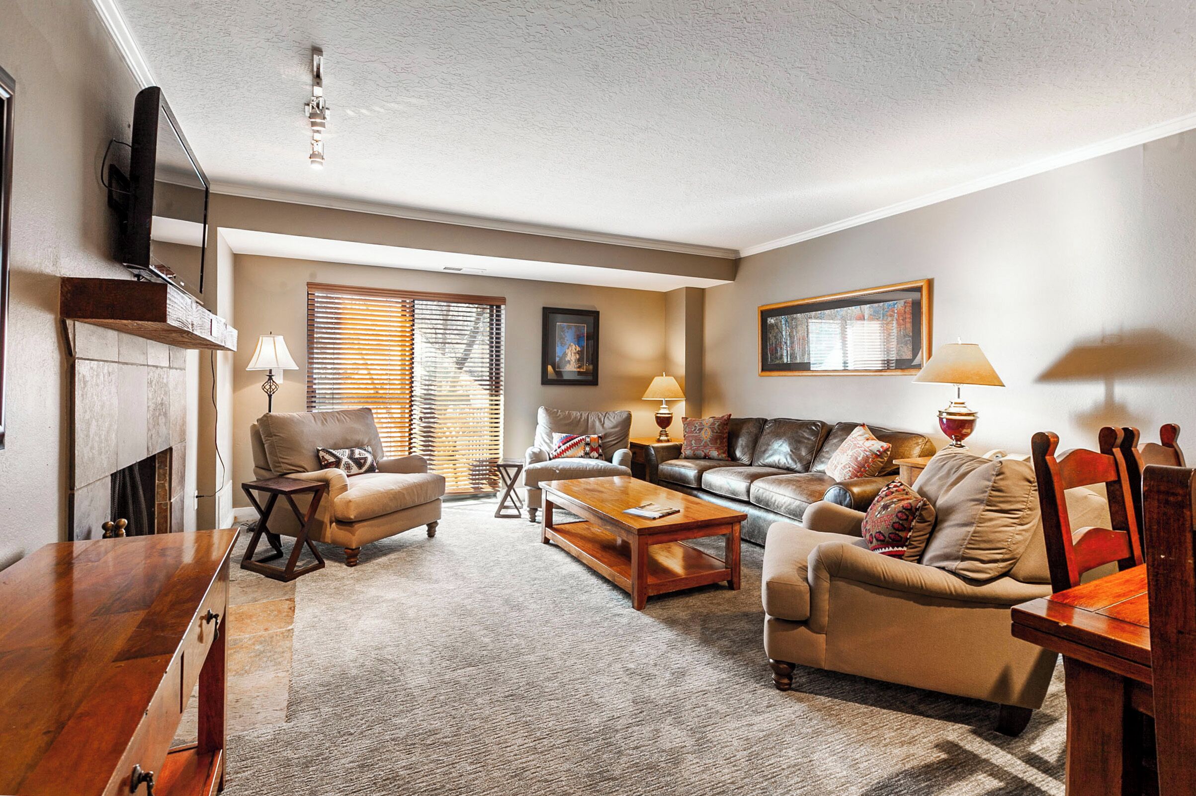 A living room with a fireplace, a sofa, a coffee table, and a television mounted on the wall.