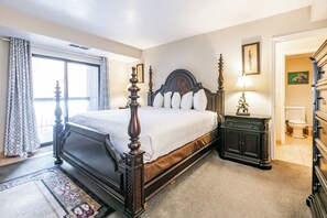 A four-poster bed with a wooden headboard, a nightstand with a lamp, and a dresser with a mirror. - Shadow Ridge 204-3 | Walk to Lifts | Kitchen | Fireplace | Pool & Hot Tub | Sauna | Fitness Room (Park City)