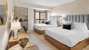 A hotel room with two beds, a dining area, and a view of the outdoors.