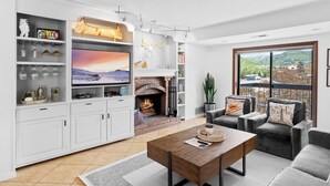 A modern living room with a fireplace, a television, and a balcony with a view. - Shadow Ridge 300-3 | Walk to Lifts | Mtn Views | Kitchen | Fireplace | Updated | Pool & Hot Tub (Park City)