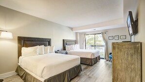 A hotel room with two beds, a TV mounted on the wall, and a view of the outdoors through the window. - Shadow Ridge 303-1 | Short Walk to Skiing | Mountain & Ski Views | Food Galley | Pool & Hot Tub (Park City)