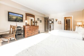 A hotel room with a large bed, a wooden dresser, a television mounted on the wall, and a chair.