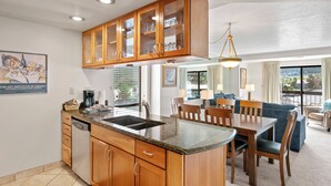 A modern kitchen with wooden cabinets, a granite countertop, and a dining area with a table and chairs.