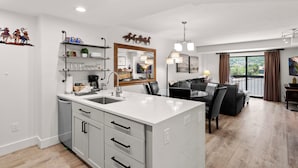 A modern kitchen with a central island, a dining area with a view, and a living room with a balcony. - Shadow Ridge 406-3 | Walk to Lifts | Mtn Views | Kitchen | Fireplace | Updated | Pool & Hot Tub (Park City)