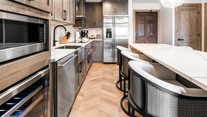Une cuisine moderne dotée d’appareils électroménagers en acier inoxydable, de meubles en bois et d’un parquet disposé en motif à chevrons.