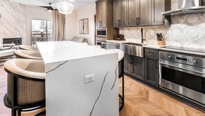 Une cuisine moderne avec des meubles en bois foncé, des appareils électroménagers en acier inoxydable et un îlot central en marbre.