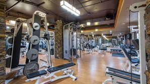 Ein Fitnessraum mit unterschiedlicher Trainingsausstattung, Holzboden und einer Ziegelwand.