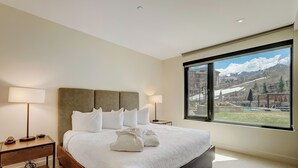 A hotel room with a large bed, two bedside tables, and a view of a ski resort. - LIFT 307-A | Ski-In/Out | Near Pool Deck | Mountain View | Hot Tub | Pool | Great Amenities (Park City)