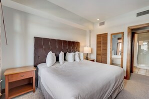 Ein ordentlich eingerichtetes Hotelzimmer mit einem großen Bett, einem Nachttisch, einer Lampe und einem Kleiderschrank.