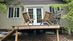 A wooden deck with two wooden chairs and a small table. - Waterfront Cottage for Rent in Parry Sound Region 
 (Pointe au Baril)