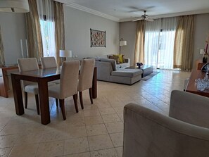 A spacious living room with a dining area, a gray sofa, a coffee table, and a ceiling fan.