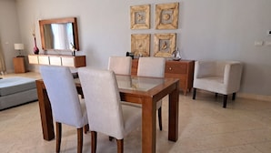 Un comedor con una mesa de madera y seis sillas, un sofá, un televisor y decoración mural.