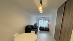 Een moderne woonkamer met een eethoek, een bank, een televisie en een balkon met uitzicht.
