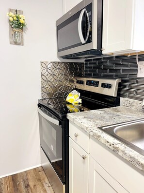 A kitchen with a built-in oven, a microwave, and a stainless steel sink.