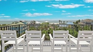 Un balcon avec des chaises blanches donnant sur une vue sur la côte.