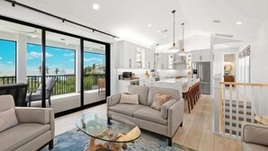 Un intérieur moderne comprenant un espace de vie, une cuisine et de grandes portes-fenêtres coulissantes donnant sur un balcon.
