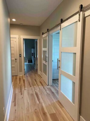 A hallway with wooden flooring and white doors with glass panels. - Luxury house, ocean view rooftop, private elevator (Carolina Beach)