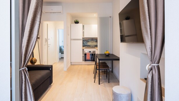 Una cocina moderna con armarios blancos, una mesa de comedor y un sofá negro.
