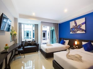 Habitación de hotel con dos camas, un sofá, un escritorio y una televisión.