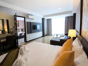 A hotel room with a bed, a desk, a TV, a sofa, and a window with curtains. - The Ozone Boutique Hotel (Udon Thani)