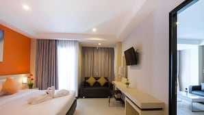 Une chambre d’hôtel équipée d’un lit, d’un bureau, d’un canapé et d’un téléviseur fixé au mur.