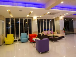 A modern lobby with a seating area featuring a sofa and chairs, large windows, and a clean, polished floor. - The Ozone Boutique Hotel (Udon Thani)