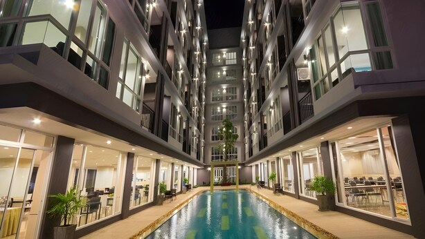 Un hôtel moderne doté d’une piscine centrale, de plusieurs étages et d’espaces extérieurs aménagés pour se détendre.