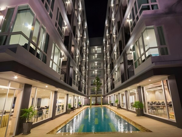 A modern hotel with a central pool, multiple floors, and outdoor seating areas. - The Ozone Boutique Hotel (Udon Thani)